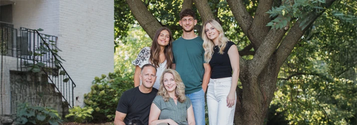 Chiropractor Lancaster PA Keith Krueger and Family Hero Dr. Keith Krueger and Sally Krueger posing with their family in a green garden of a house.
